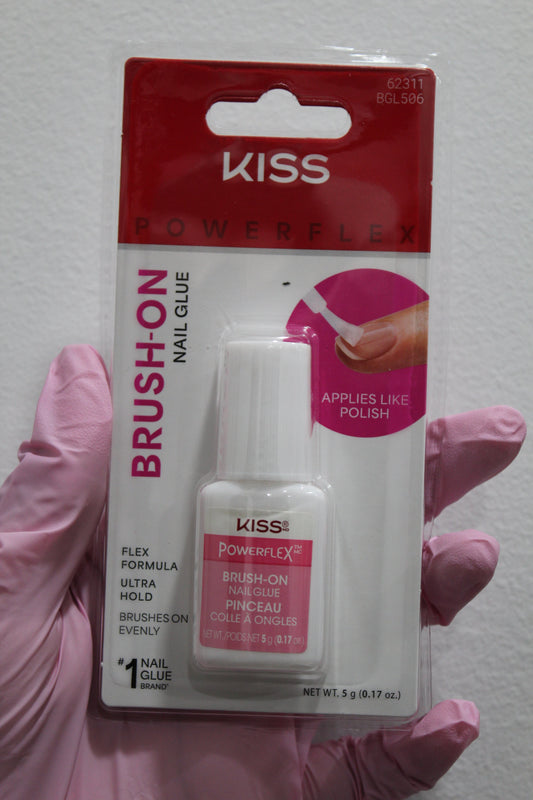 Kiss Brush-On Nail Glue packaging held by a gloved hand on a white background